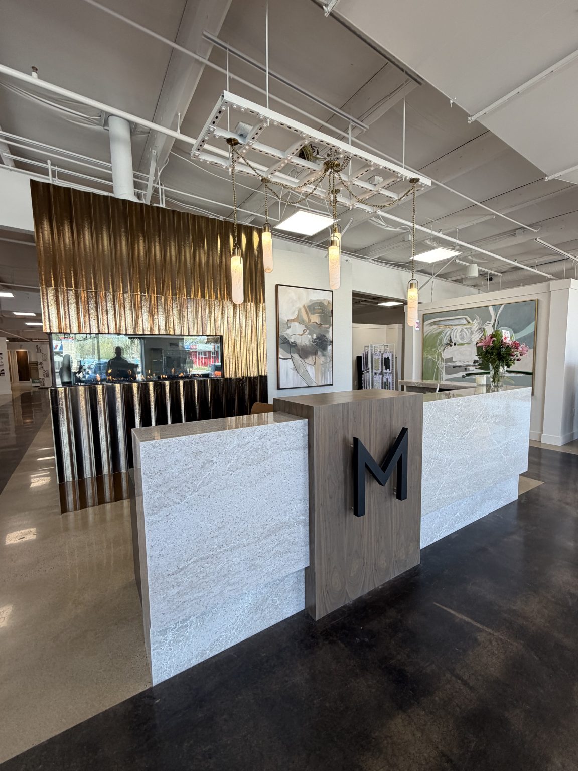 Custom walnut and quartz waterfall-edge reception desk with backlit “M” logo at Montgomery's Furniture Gallery in Sioux Falls, SD.