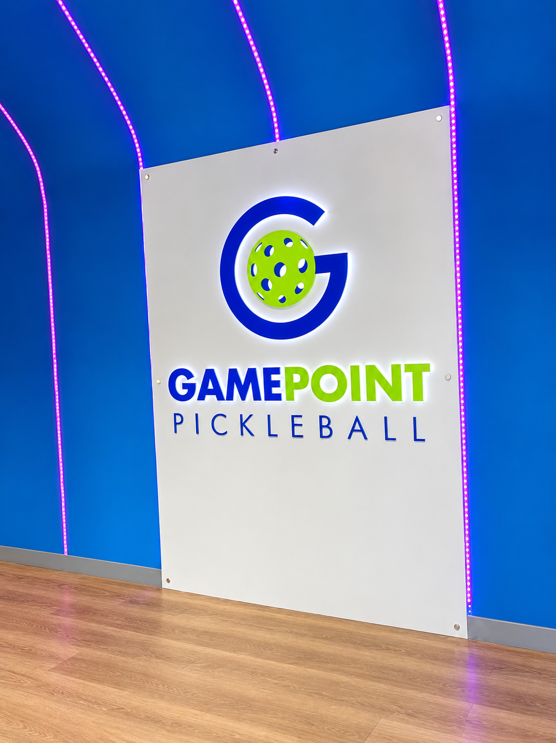 Illuminated GamePoint Pickleball logo panel on a blue wall with LED accent lines
